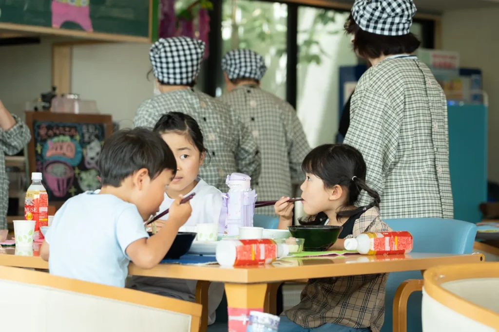 こども食堂「おかえり」のテーブルを囲み、スタッフに見守られながら美味しそうに食事をする子どもたち