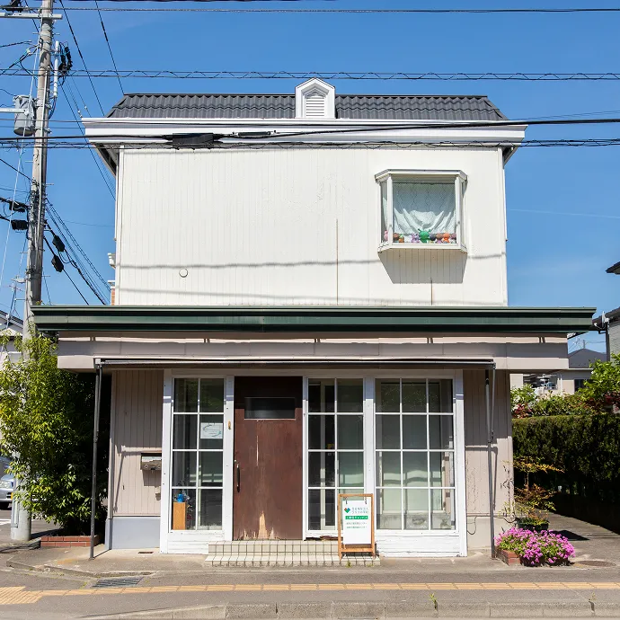 青空のもと、住宅街に馴染むアットホームな佇まいをした「上飯田キャンパス」の建物外観