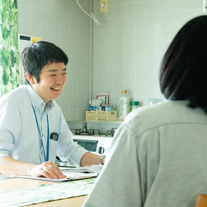 明るいキッチンカウンター越しに、利用者たちと温かい笑顔で楽しそうに会話を交わすスタッフ