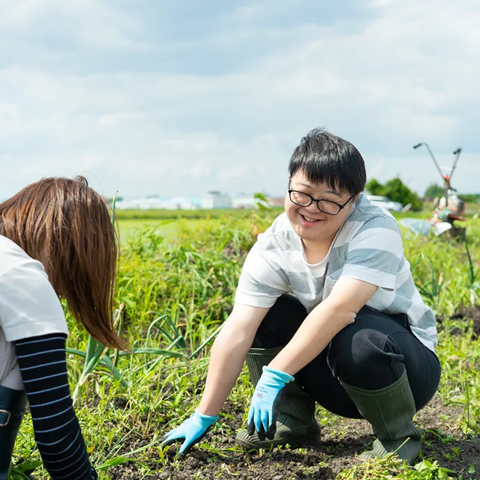 作業の合間に、隣のスタッフと顔を見合わせて生き生きとした満面の笑顔を見せる姿