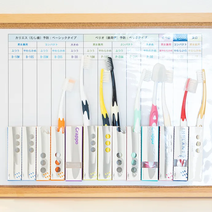 むし歯や歯周病などの予防タイプ別に、様々な種類の歯ブラシが分かりやすく分類された木枠の案内ボード